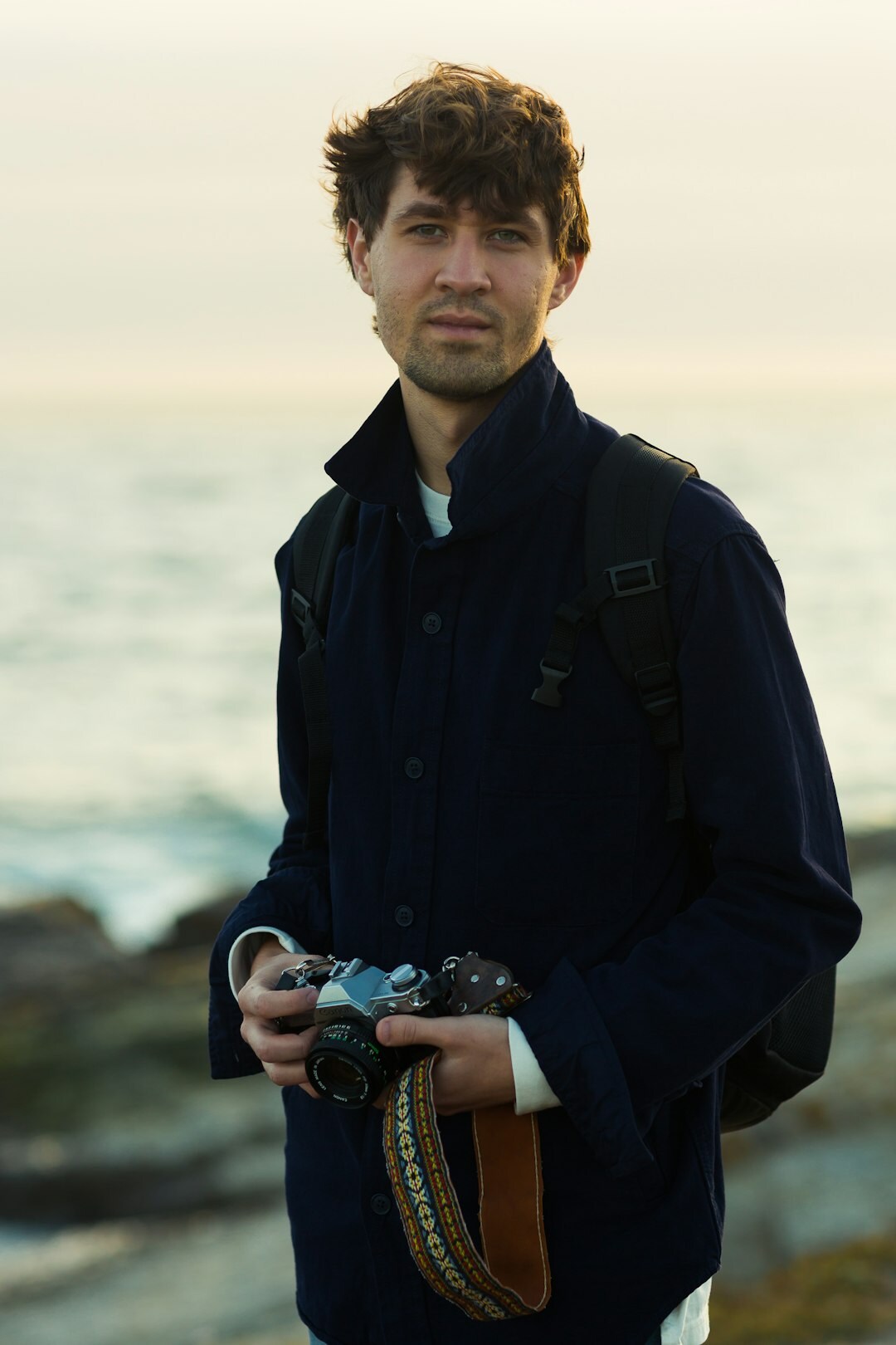Portrait of a Chilean documentary photographer in his thirties holding a film camera